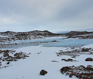 Brown hills, snow and ice under a cloudy sky