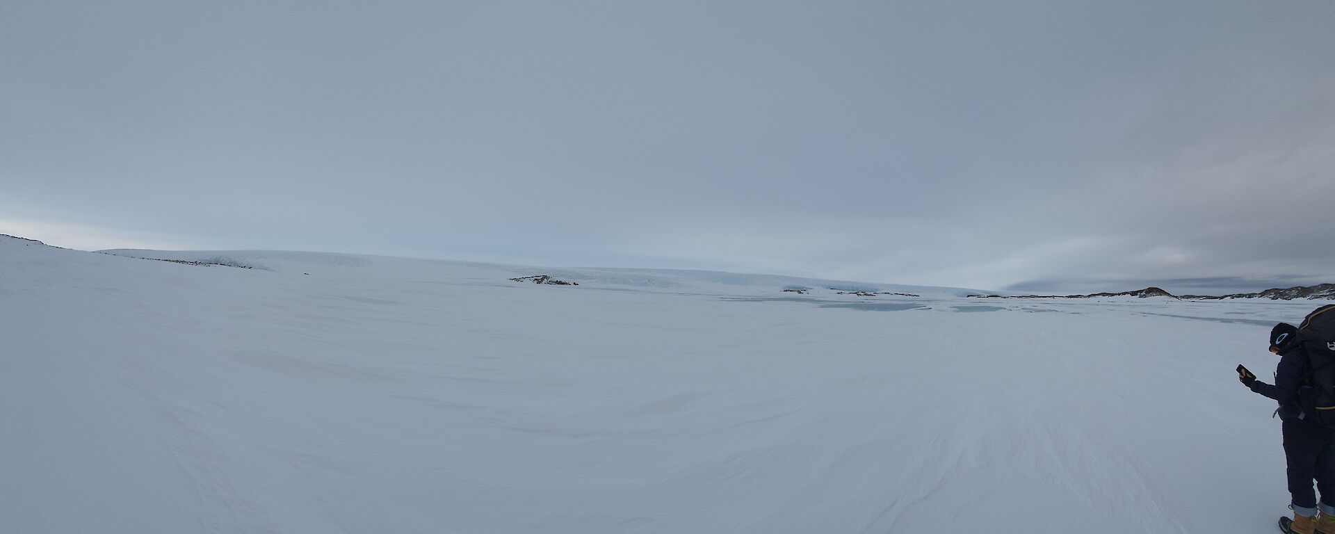 A person with a backpack looking out to a glacier from ground level