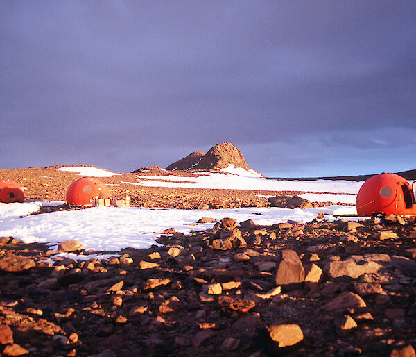 Round red huts shaped like an apple nestled in the rocky hills