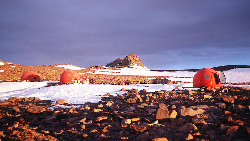 Round red huts shaped like an apple nestled in the rocky hills