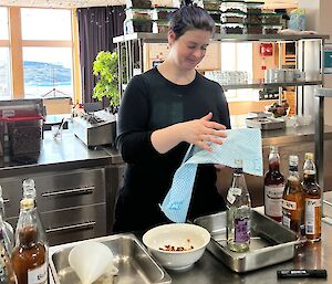 Lady stands at kitchen bench with bottles and funnels preparing kombucha brew