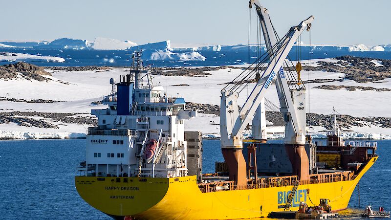 A yellow ship floats in an icy bay.