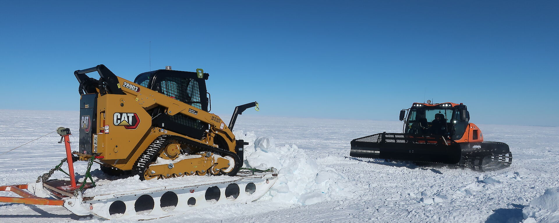 Snow groomer and skid steer on a plateau of ice