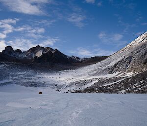 Large frozen lake with Hägglunds in distance, with large mountain peaks rising up above the lake