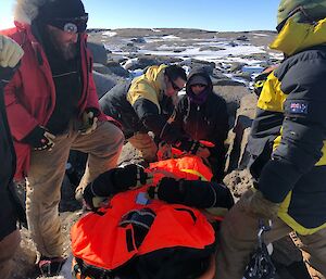 Stretcher carry underway with six people carrying over rocky ground the injured person