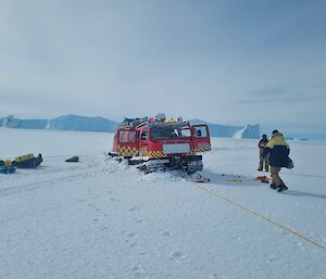 Hägglunds vehicle bogged in snow, attached to winch