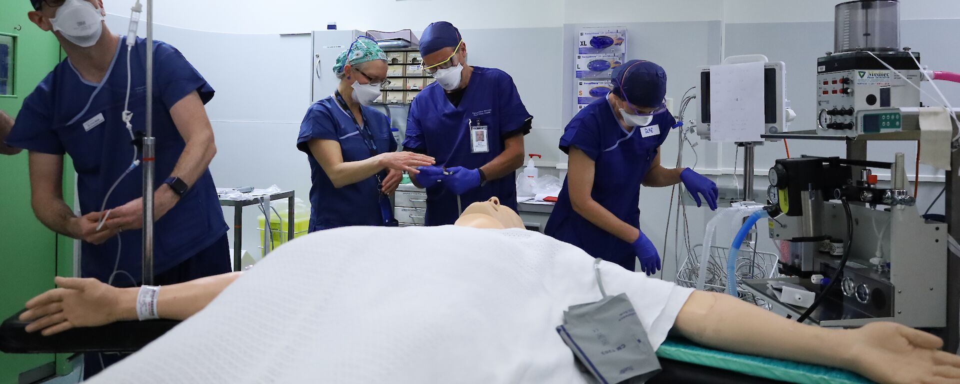 People in blue hospital gowns prepare for a mock surgery operation