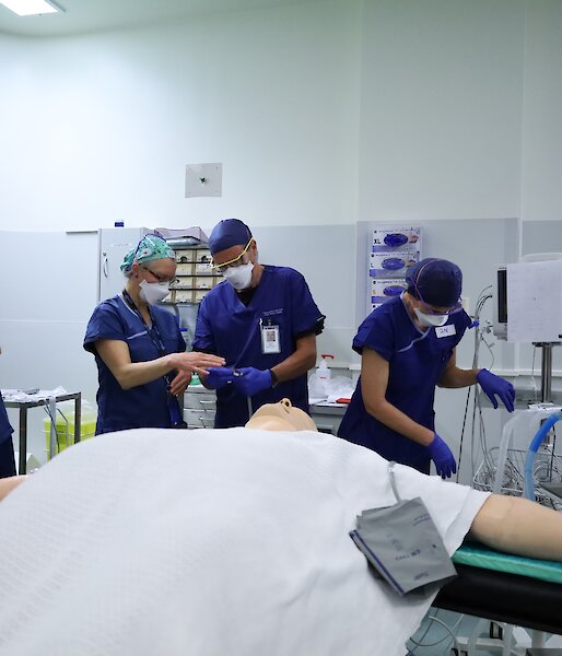 People in blue hospital gowns prepare for a mock surgery operation
