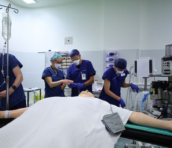 People in blue hospital gowns prepare for a mock surgery operation