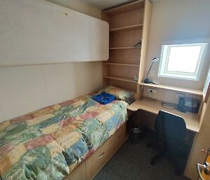 A bedroom with a single bed and a small desk and window awaits the next expeditioner