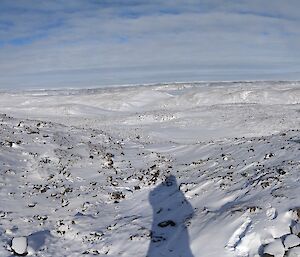 A panoramic shot of the snowy hills with a couple of men looking at a science instrument