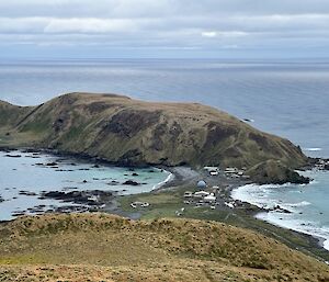 A view of Macquarie Island research station taken from atop a hill under patchy grey skies