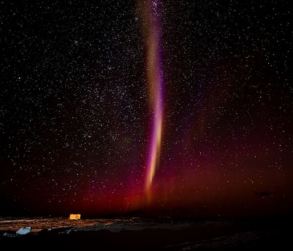 A pinkish-white vertical streak in the night sky.