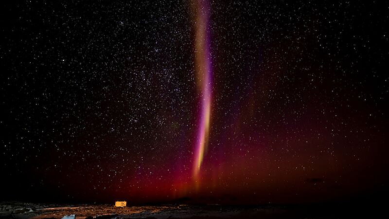 A pinkish-white vertical streak in the night sky.