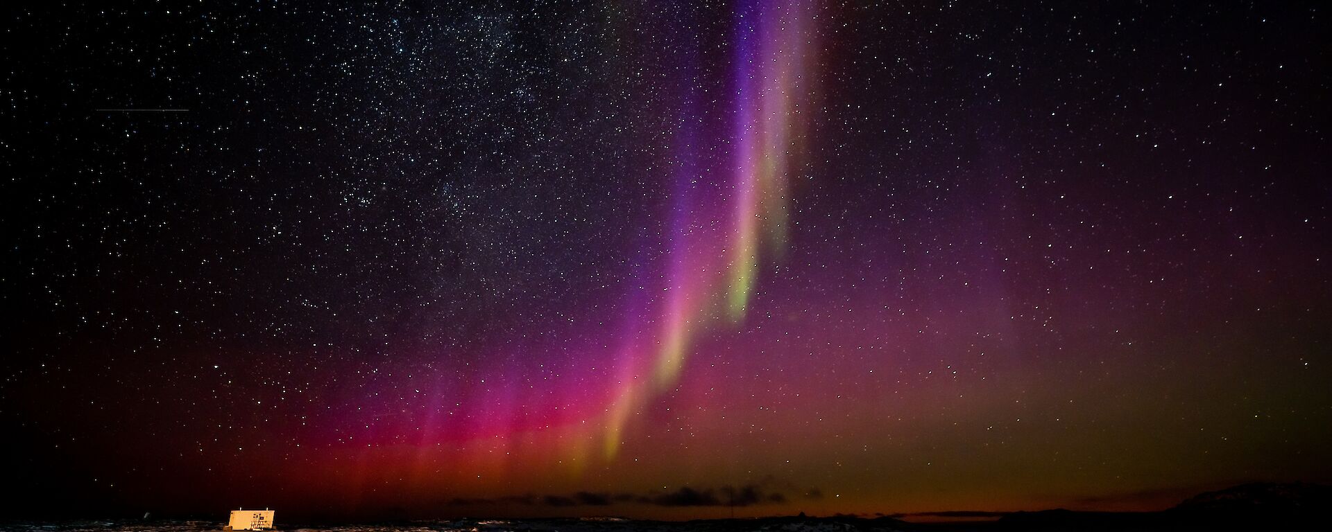A pinkish-white arc in the night sky