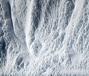 A close up of an ice cliff with clumps of snow stuck on it after a blizzard