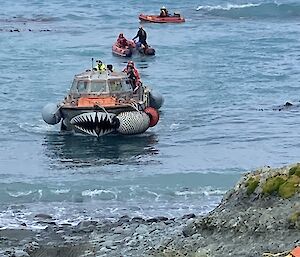 Three small boats are heading to shore to deliver supplies to the island