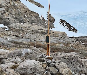A rocky cairn with a timber post sits lonely in the landscape
