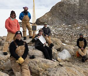 Six people stand in a group following the steps of an Antarctic legend