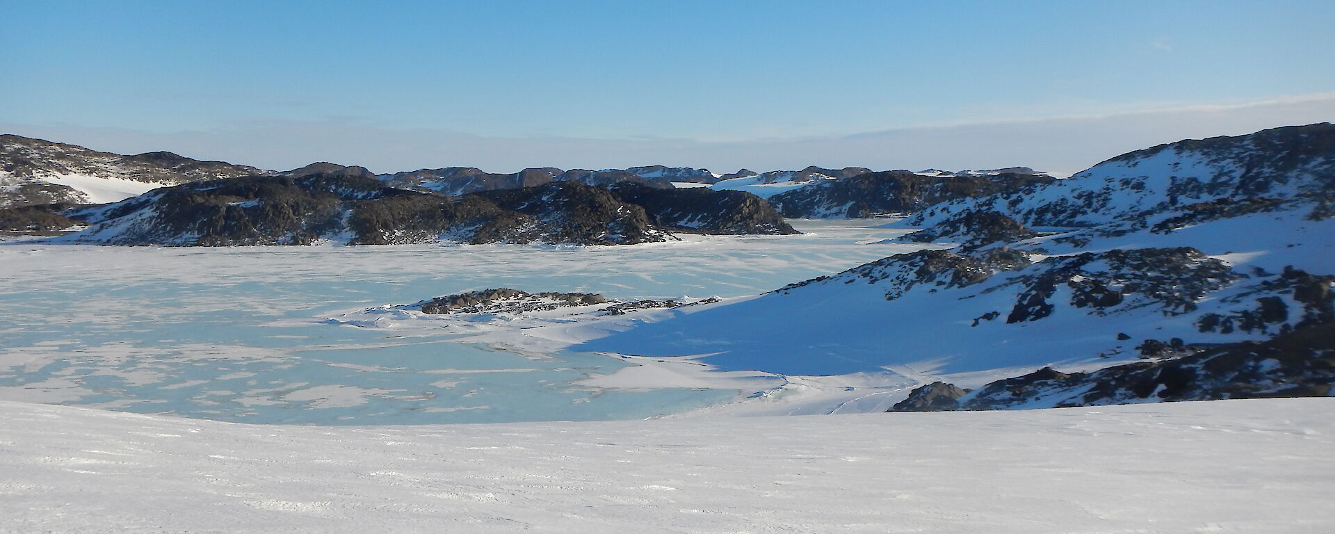 A landscape of snow with rocks and hills in the background