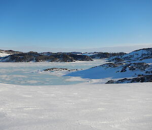 A landscape of snow with rocks and hills in the background