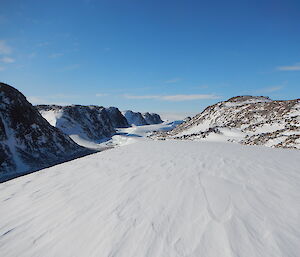 a landscape of snow with rocks and hills in the background