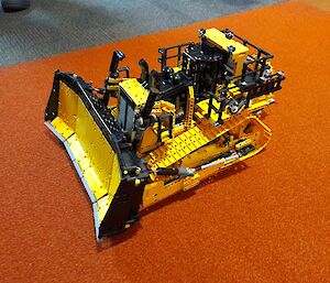 A yellow and black model bulldozer built from a hobby construction kit