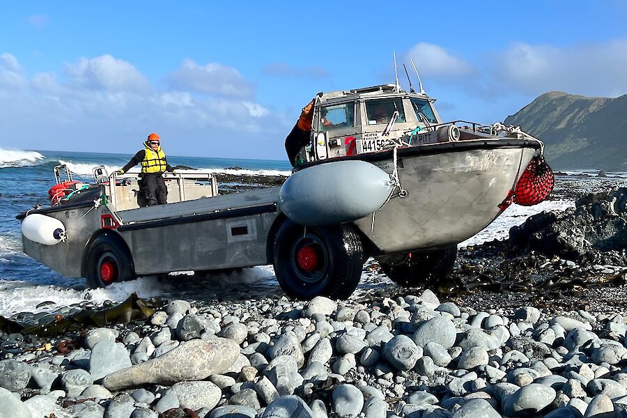 An amphibious vehicle driving out of the surf on to a pebble beach