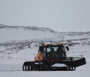 A yellow and black snow groomer at work on the sea ice