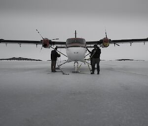 Small propellered plane from front on with person standing either side of nose