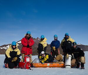 Group of 7 people posing and looking to camera, mountain range in background