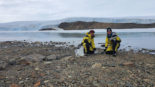 Two women scientists collecting specimens from soil in Antarctica.