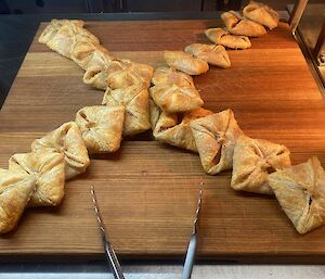 Lines of square apricot tarts arranged on a wooden serving board in the shape of an 'X'