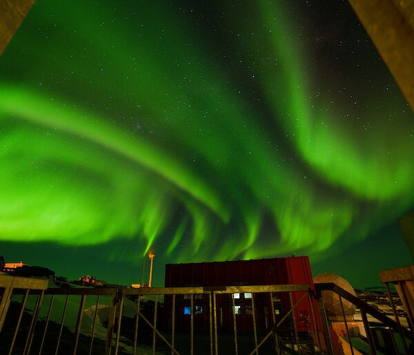 Aurora lights over Mawson station emergence vehicle shed and wind turbine