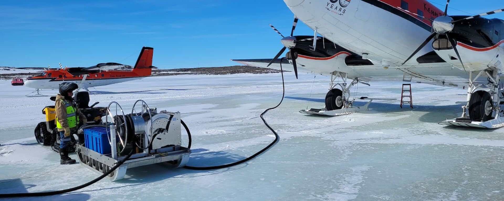 Two red and white planes on the sea ice refuelling
