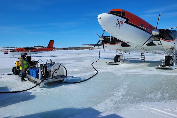 Two red and white planes on the sea ice refuelling