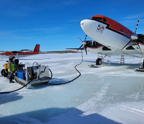 Two red and white planes on the sea ice refuelling