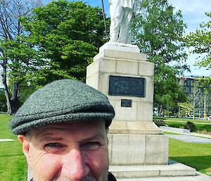 A person in a cap in front of statue