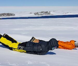 Two people laying face down in snow