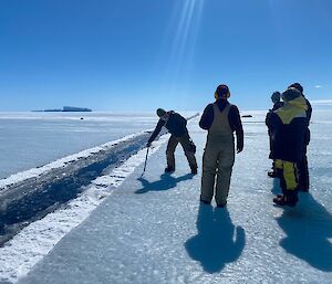 A group of people stand on the sea ice