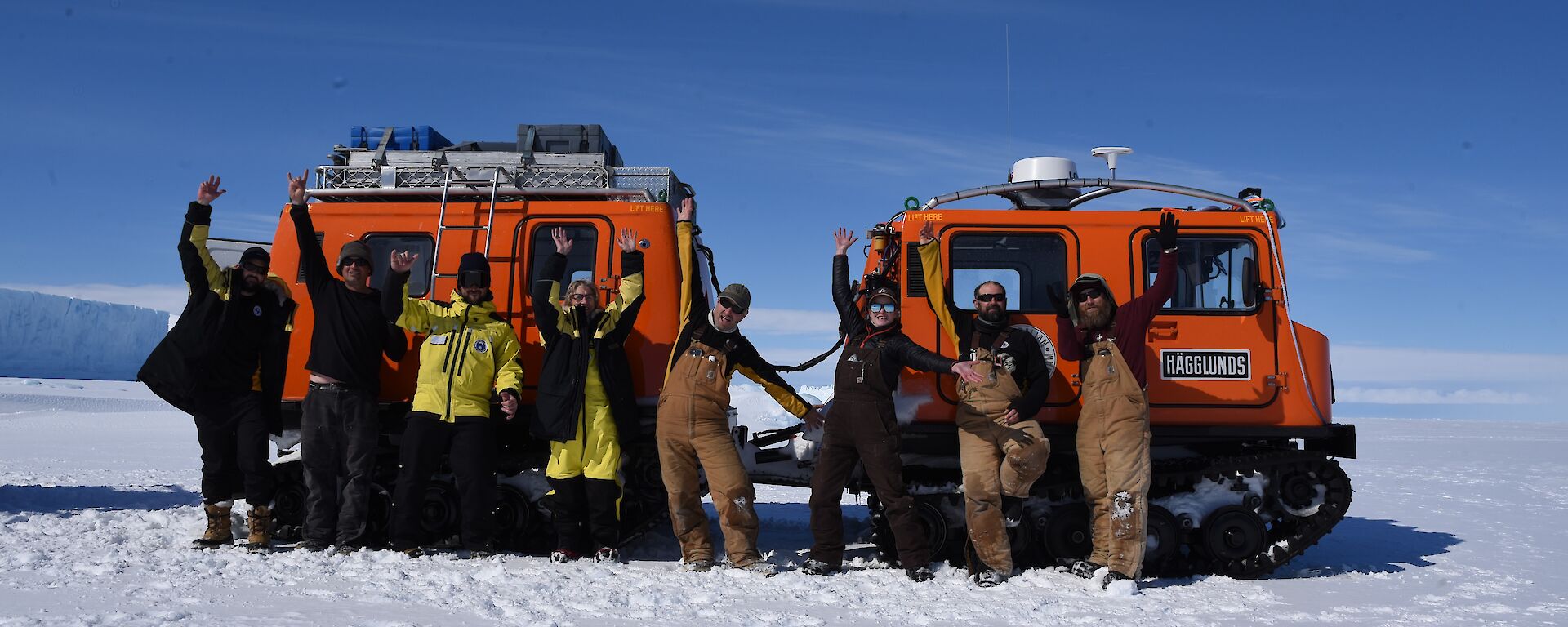 A group of people stand in front a red vehicle on the sea ice