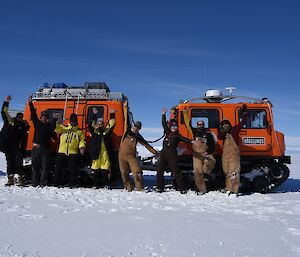 A group of people stand in front a red vehicle on the sea ice