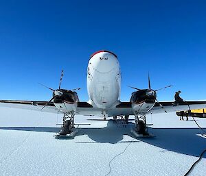 A plane sits on the ice while being refuelled on a sunny day