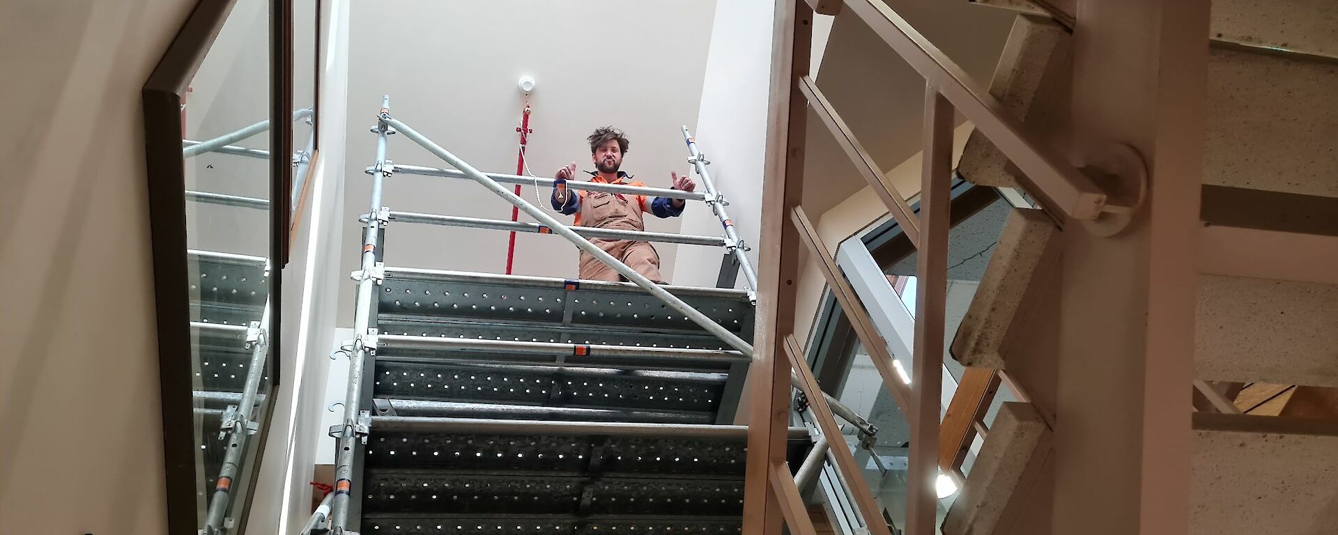 Looking up from below to carpenter standing at top of scaffolding tower