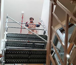 Looking up from below to carpenter standing at top of scaffolding tower