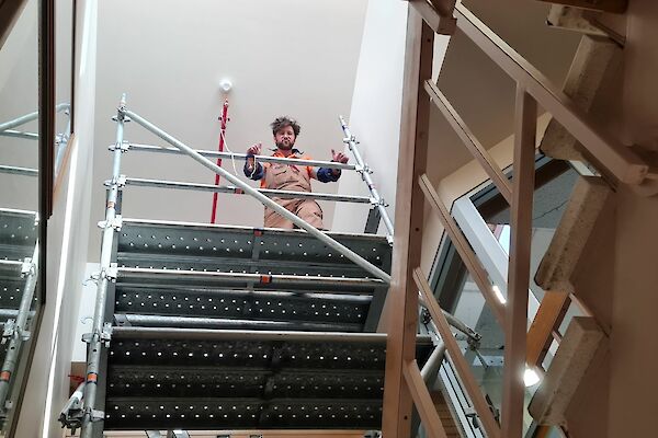 Looking up from below to carpenter standing at top of scaffolding tower