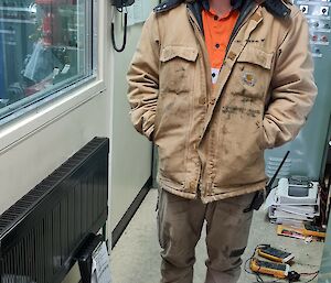 Man stands in control room of power house, wearing hearing protection and smiling to camera