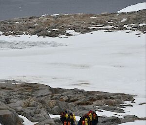 People walking over rocks and snow