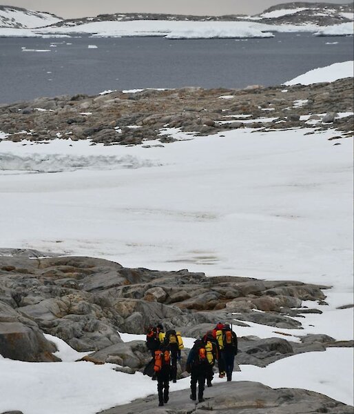 People walking over rocks and snow