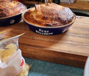 A crispened pie in a dish on top of a wooden board